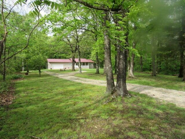 7210 Newkirk Rd, Mountain Grove, MO 65711 - view of front of house with a front lawn, a garage, driveway, and a view of trees