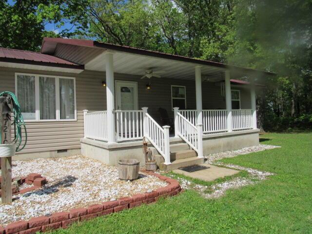 7210 Newkirk Rd, Mountain Grove, MO 65711 - view of front facade with metal roof, ceiling fan, covered porch, crawl space, and a front lawn