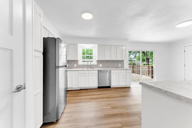 1107 E Mccracken Rd, Ozark, MO 65721 - kitchen with white cabinets, appliances with stainless steel finishes, decorative backsplash, and a healthy amount of sunlight