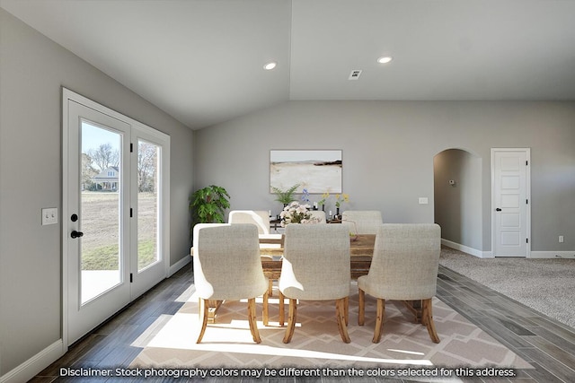 dining room with arched walkways, baseboards, vaulted ceiling, and wood finished floors