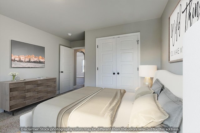 carpeted bedroom with arched walkways and a closet