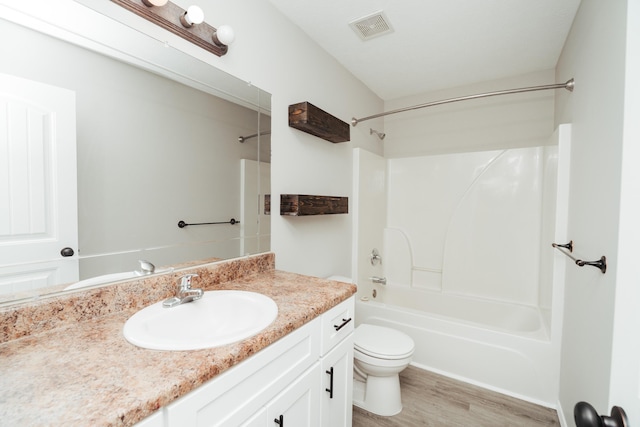 bathroom with shower / bathing tub combination, visible vents, wood finished floors, vanity, and toilet