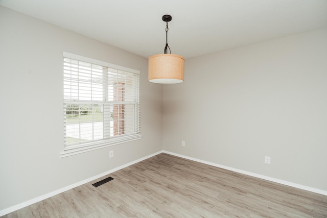 empty room featuring baseboards, wood finished floors, and visible vents
