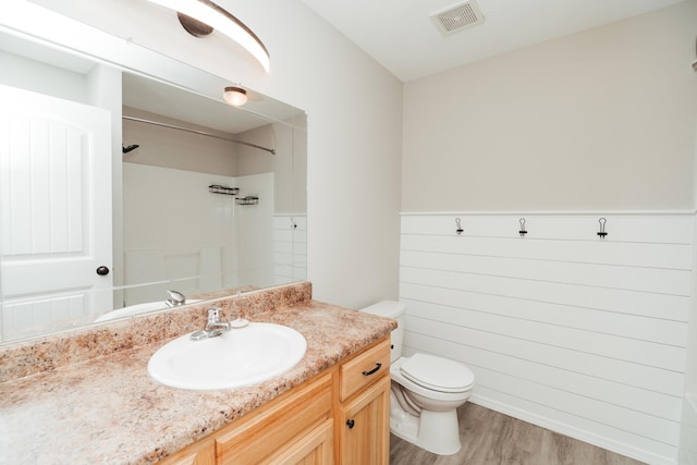full bath featuring visible vents, walk in shower, wood finished floors, vanity, and toilet