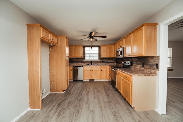 kitchen featuring a ceiling fan, light wood-style floors, tasteful backsplash, a sink, and stainless steel appliances