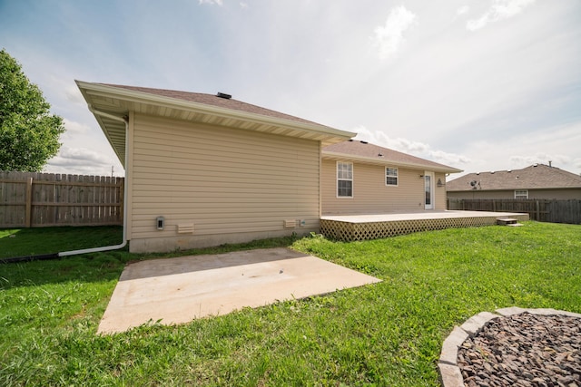 rear view of house with a lawn, a deck, a fenced backyard, and a patio area