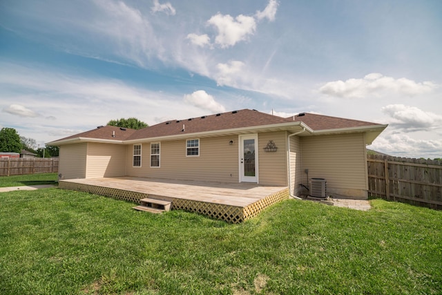 rear view of house featuring central AC, fence, a wooden deck, roof with shingles, and a lawn