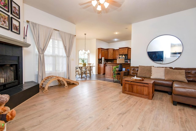 1376 N 14th St, Ozark, MO 65721 - living area with a tiled fireplace, light wood finished floors, and ceiling fan with notable chandelier