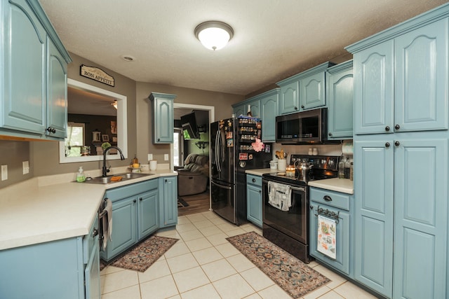 kitchen with a sink, light countertops, stainless steel appliances, and light tile patterned flooring