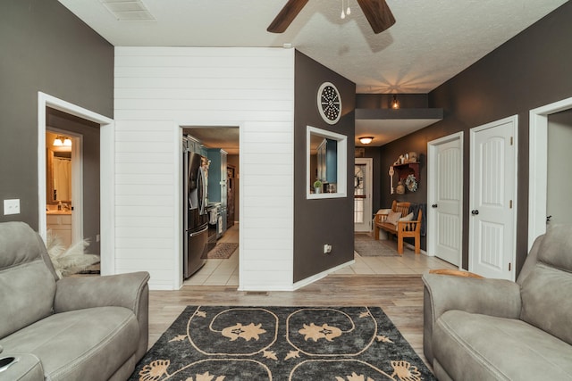 living area featuring ceiling fan, light wood-type flooring, and visible vents