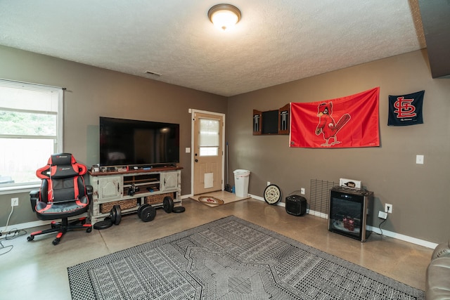 living area with a textured ceiling, baseboards, and finished concrete flooring