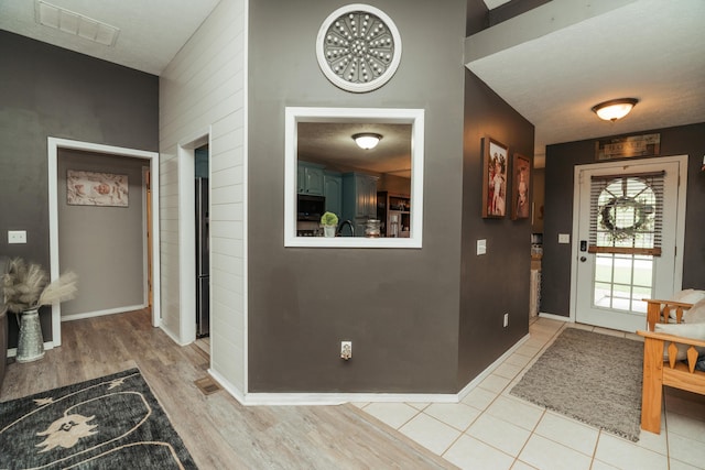 foyer featuring visible vents, light wood-style flooring, and baseboards