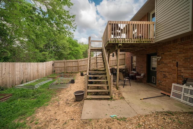 view of yard featuring a wooden deck, a patio, a fenced backyard, a vegetable garden, and stairway