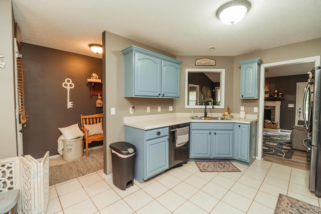 kitchen featuring a sink, dishwashing machine, blue cabinets, and light countertops