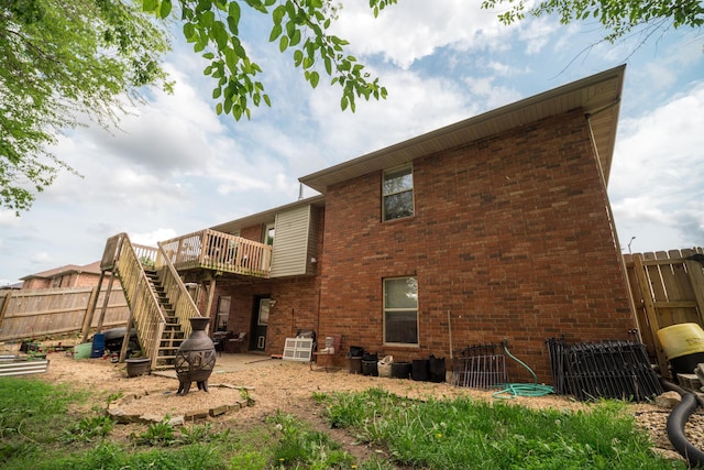 back of property featuring brick siding, stairway, fence, and a deck