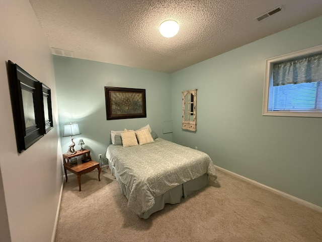 carpeted bedroom featuring baseboards, a textured ceiling, and visible vents