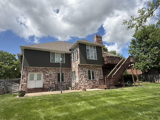 rear view of house featuring fence, a wooden deck, a chimney, and a yard