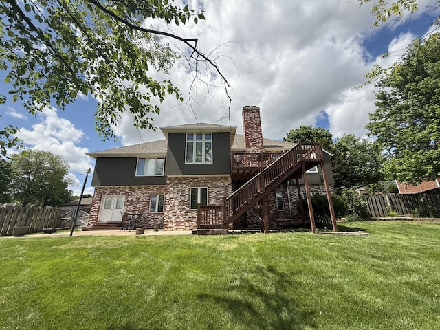 rear view of property featuring stucco siding, stairway, a fenced backyard, a chimney, and a yard