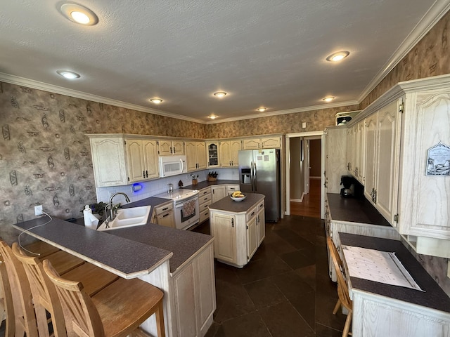 kitchen with wallpapered walls, white appliances, a sink, a peninsula, and dark countertops