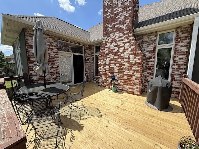 wooden terrace featuring outdoor dining area and a grill