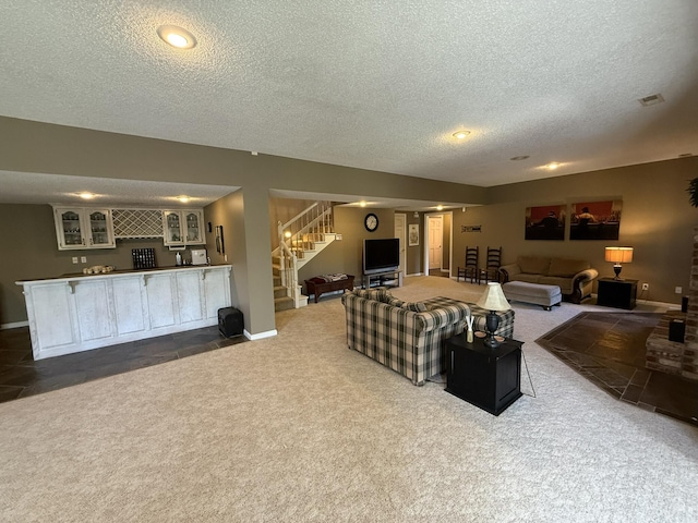 living area with dark carpet, wet bar, stairway, and a textured ceiling
