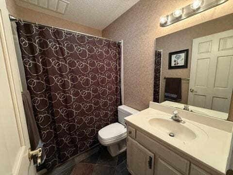 full bathroom with vanity, toilet, and a textured ceiling