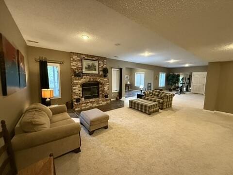 living area featuring light colored carpet, a textured ceiling, baseboards, and a fireplace