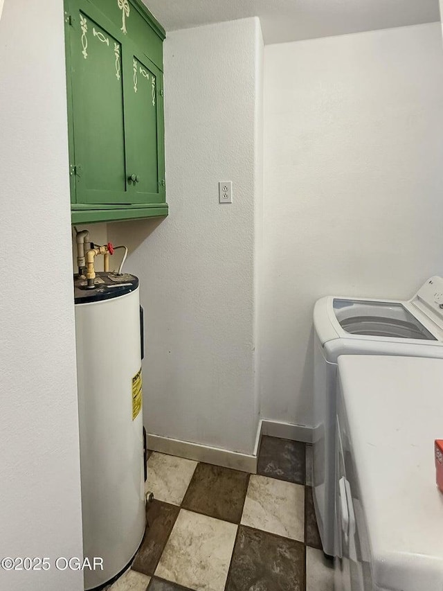 washroom with cabinet space, washer and dryer, stone finish floor, water heater, and baseboards