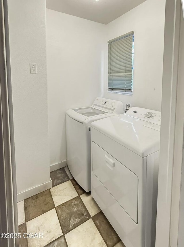 washroom featuring stone finish floor, baseboards, and washer and clothes dryer