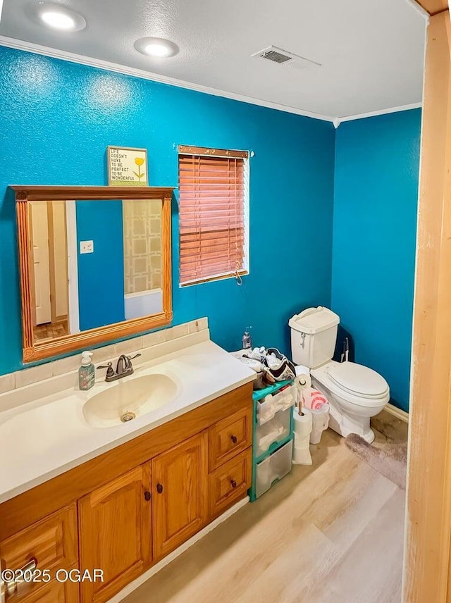 bathroom with vanity, ornamental molding, wood finished floors, and toilet