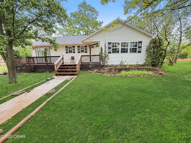 view of front of home with roof with shingles, a front yard, and a deck