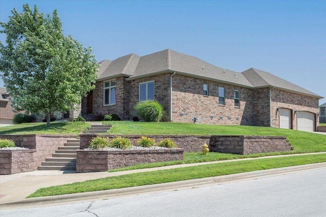 view of front facade with stairs, brick siding, an attached garage, and a front yard