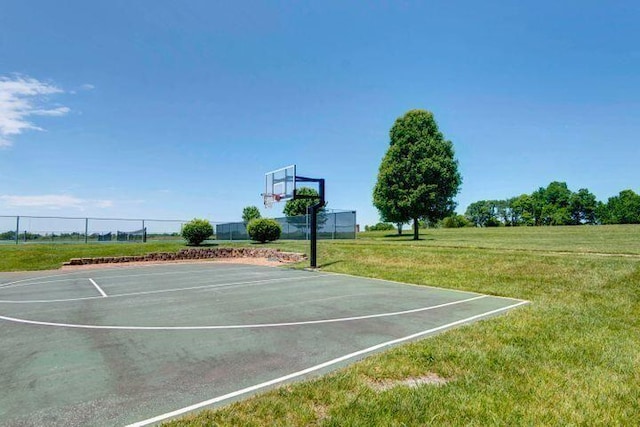 view of basketball court featuring a lawn, fence, and community basketball court