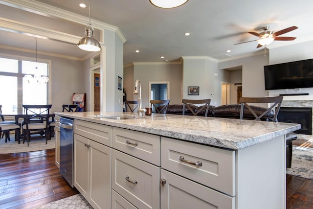 kitchen with hanging light fixtures, light stone counters, a sink, dark wood finished floors, and open floor plan
