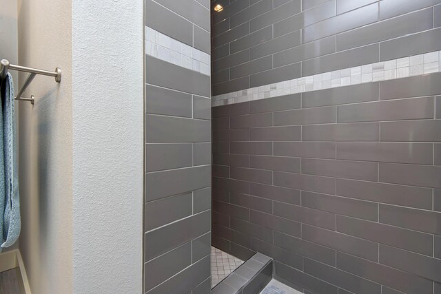 full bath with a textured wall and tiled shower
