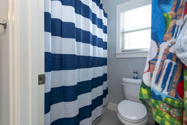 full bath with toilet and a shower with shower curtain