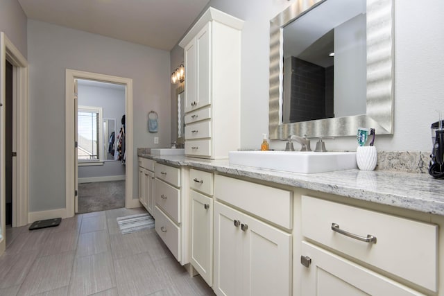 full bath featuring double vanity, a sink, and baseboards