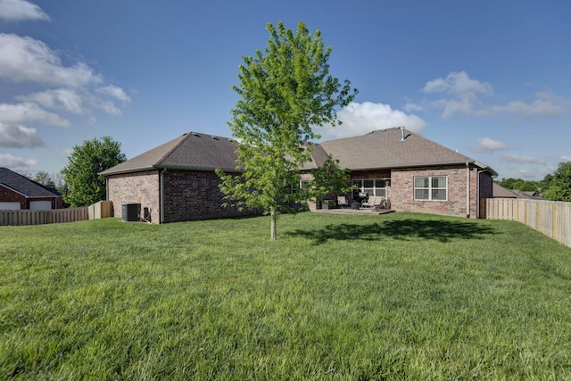 rear view of property with a lawn, brick siding, and a patio area