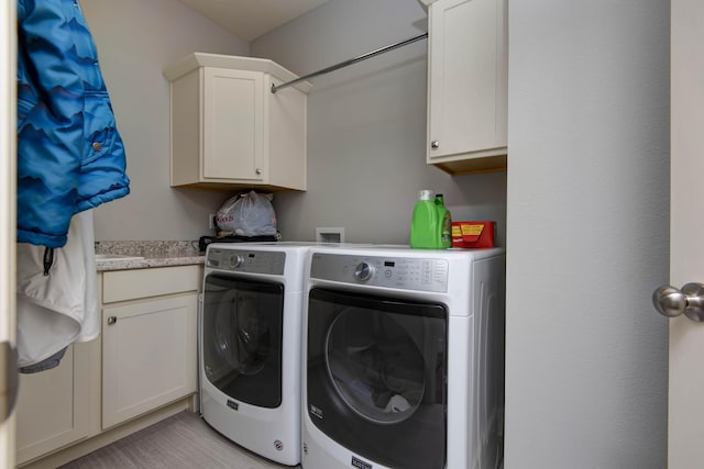 clothes washing area featuring cabinet space and washer and clothes dryer