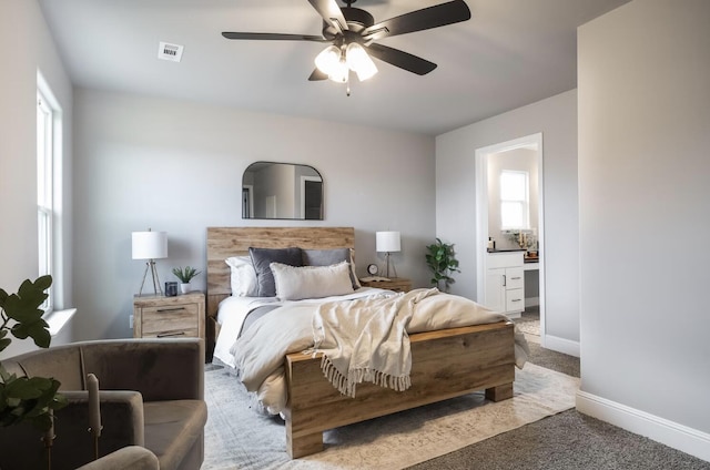 carpeted bedroom featuring visible vents, a ceiling fan, baseboards, and ensuite bath