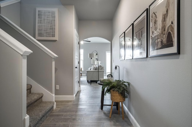 foyer entrance with visible vents, wood finished floors, baseboards, stairway, and arched walkways