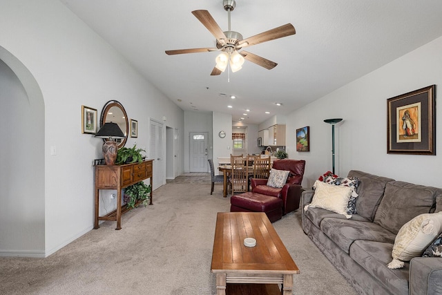 living area featuring ceiling fan, light colored carpet, arched walkways, baseboards, and recessed lighting