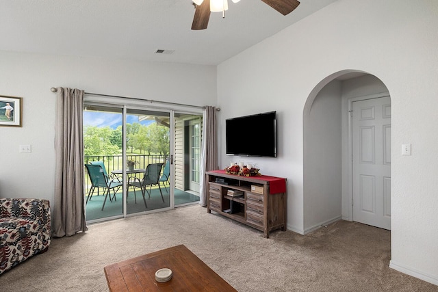 carpeted living room featuring visible vents, arched walkways, baseboards, and ceiling fan