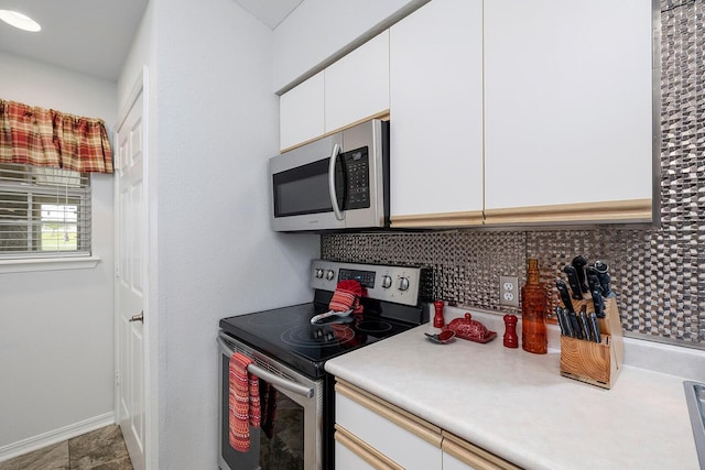 kitchen with white cabinets, appliances with stainless steel finishes, light countertops, baseboards, and decorative backsplash