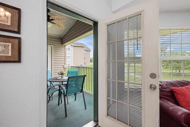 doorway to outside with carpet floors, plenty of natural light, and lofted ceiling