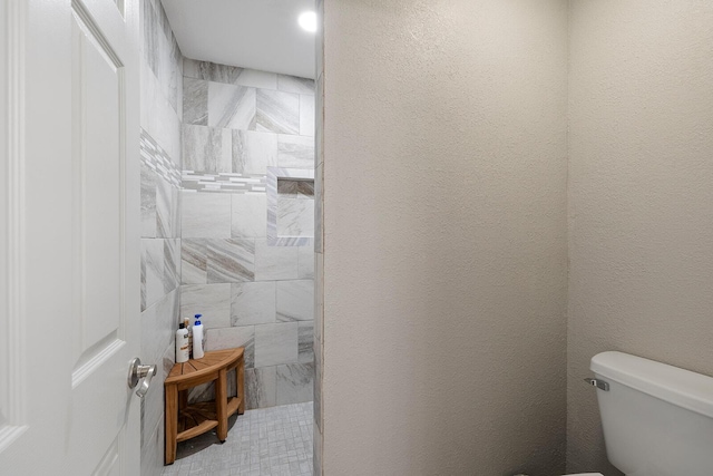 full bath with toilet and a tile shower