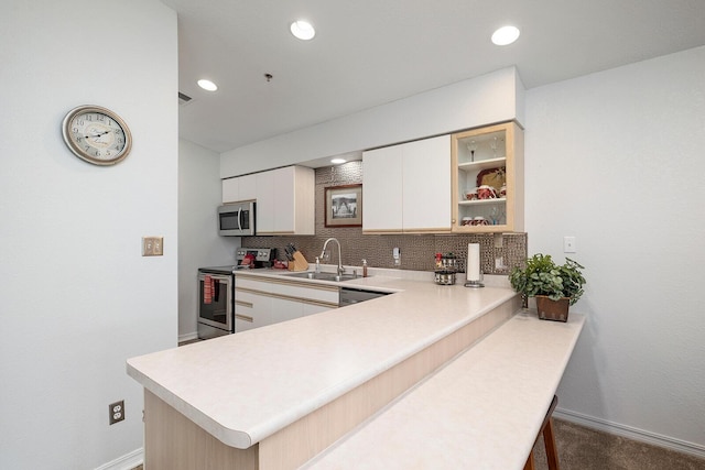 kitchen with decorative backsplash, baseboards, light countertops, a sink, and stainless steel appliances