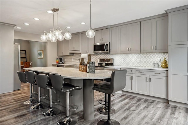 kitchen featuring appliances with stainless steel finishes, gray cabinets, a kitchen island, and wood finished floors