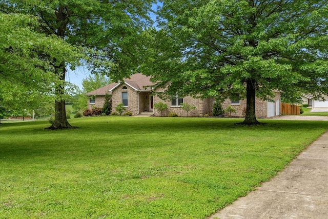 single story home featuring brick siding, a garage, a front lawn, and concrete driveway