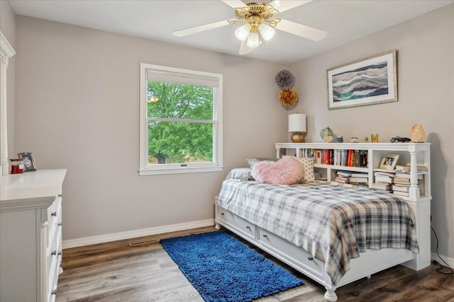 bedroom featuring baseboards, a ceiling fan, wood finished floors, and visible vents